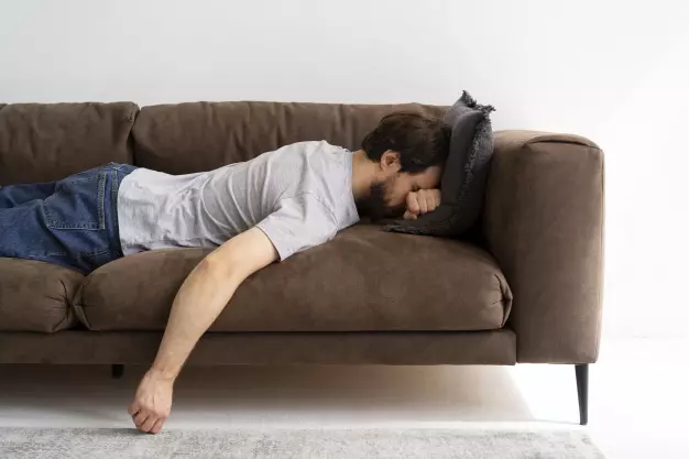 uomo stanco sul divano non ha voglia di fare esercizio fisico